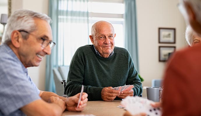 some happy elderly individuals seated in a room playing cards