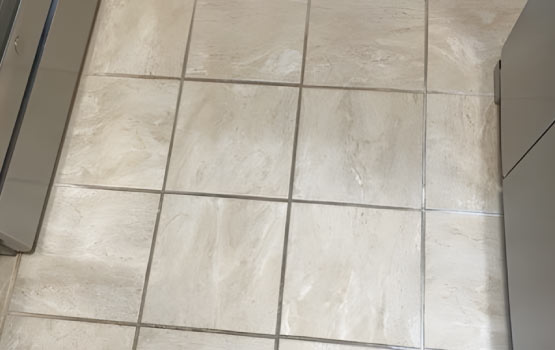 A dirty limestone tile floor with visible stains and dirt