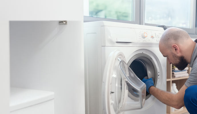 A person inspecting the inside of a washing machine