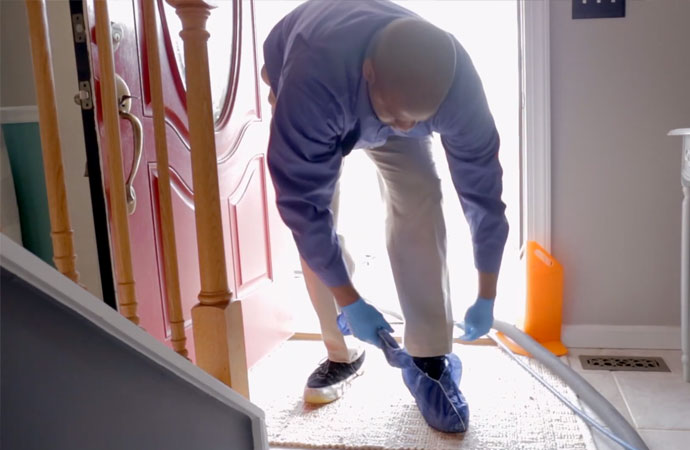 Man wearing protective shoe covers while entering the home