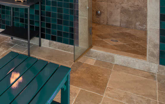 A clean limestone tile floor with a green table and a shower area in the background. 